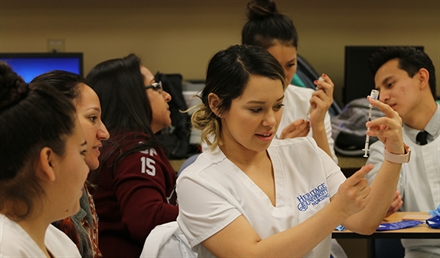 Nursing student looking at syringe Nursing student looking at syringe