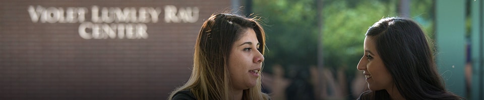 Two female students outside of Violet Lumley Rau Center at heritage university