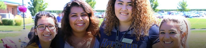 Four female Heritage University students smiling at camera