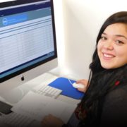 Female student sitting in front of computer smiling at camera