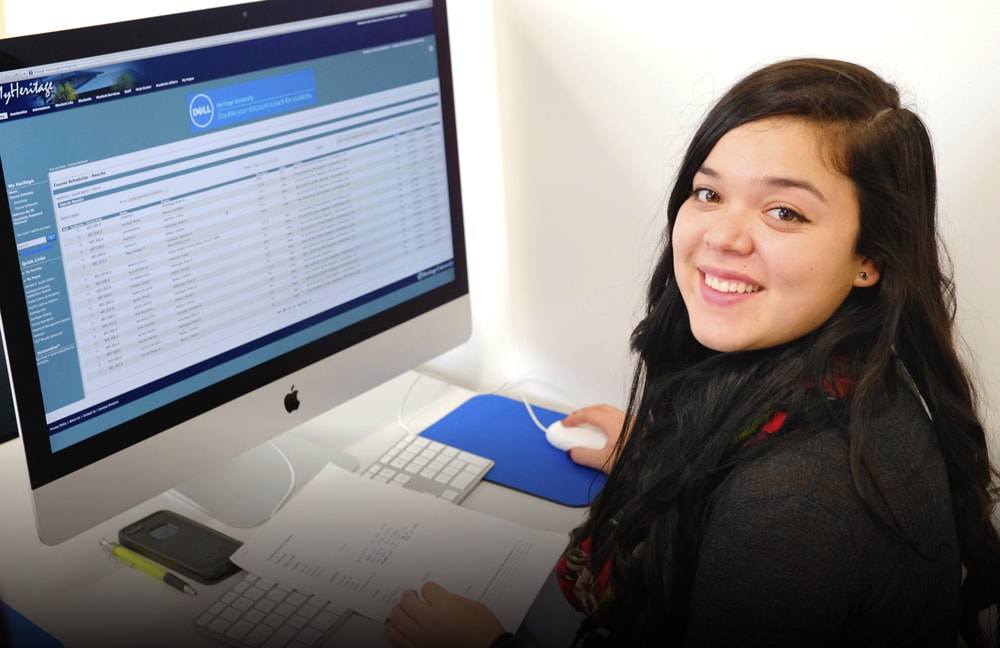 Female student sitting in front of computer smiling at camera
