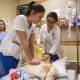 A female nursing student holds up a beaker and examines the contents.