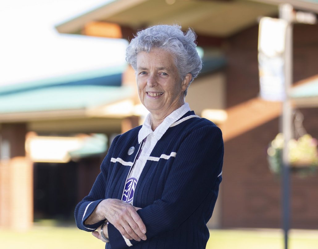 Kathleen Ross, snjm stands outside the Gaye and Jim Pigott Commons at Heritage University