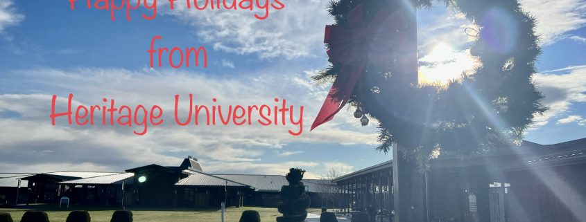A picture of a holiday wreath on a pole near the Heritage University Labyrinth with the words "Happy Holidays from Heritage University